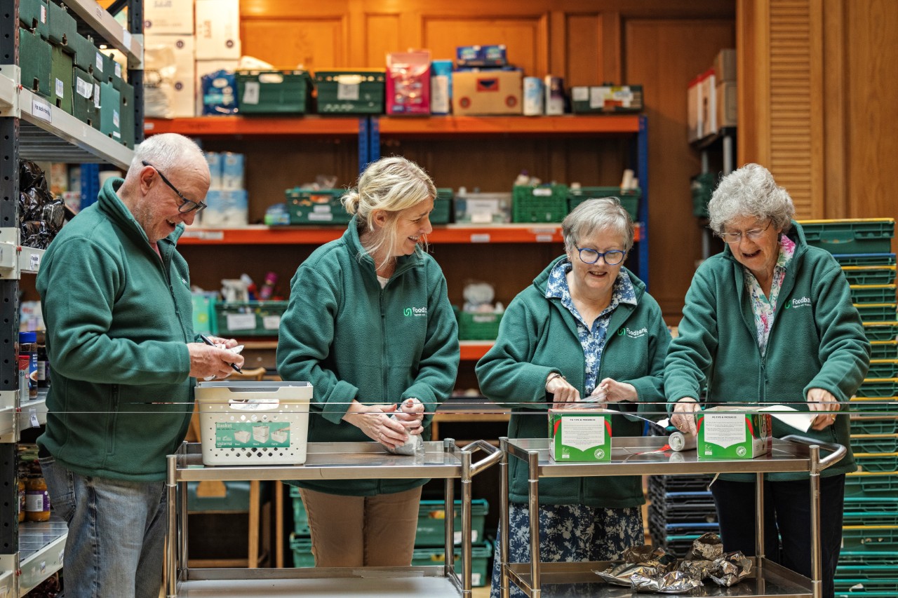 Volunteers sorting food items into crates inside a warehouse storage area